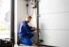 Homeowner placing wooden test block under garage door to test auto-reverse contact safety feature during monthly maintenance check