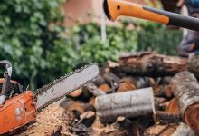 A rope chain saw lying on a wooden table, surrounded by outdoor tools, ready for home and garden use