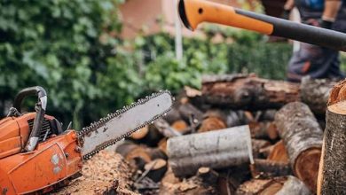 A rope chain saw lying on a wooden table, surrounded by outdoor tools, ready for home and garden use