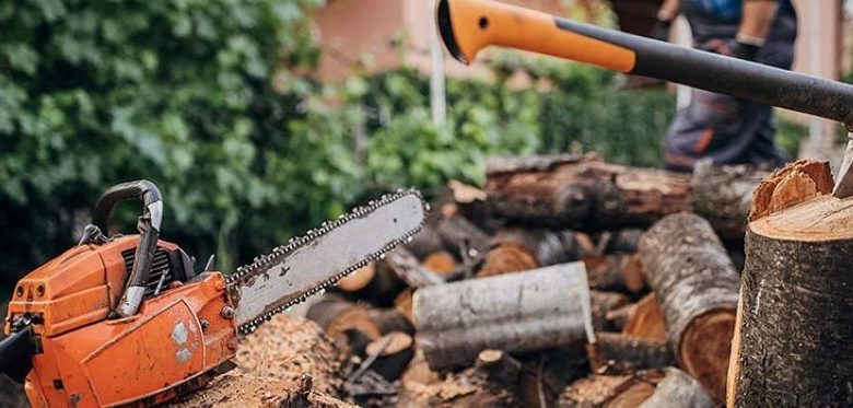 A rope chain saw lying on a wooden table, surrounded by outdoor tools, ready for home and garden use