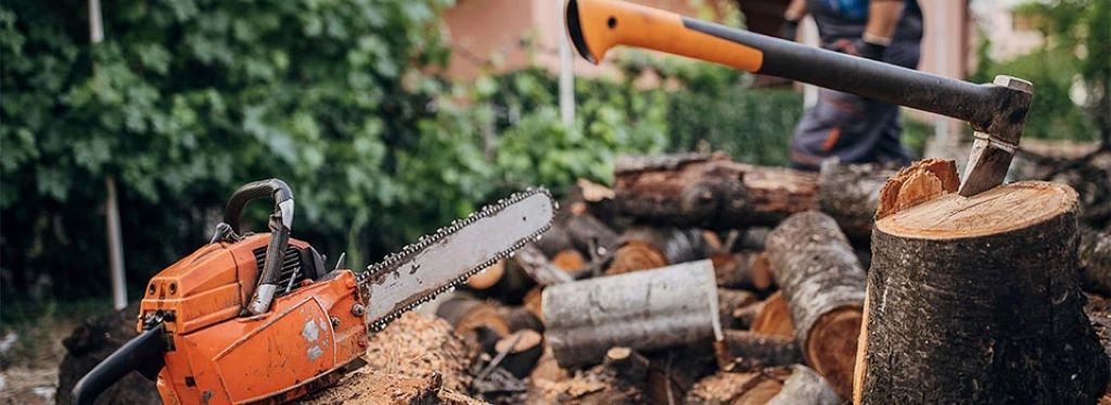 A rope chain saw lying on a wooden table, surrounded by outdoor tools, ready for home and garden use