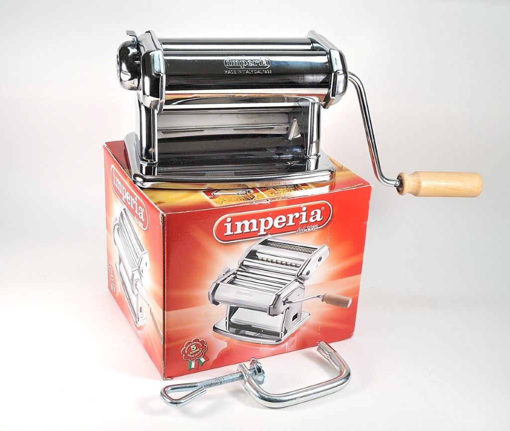 Close-up of Imperia pasta maker rollers and hand crank in use.