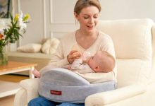 A new mother using ergonomic nursing support with a memory foam pillow during a comfortable breastfeeding session in a cozy chair.