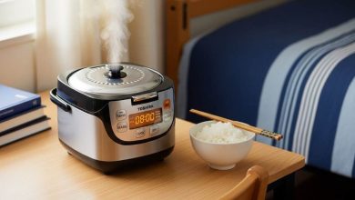 Compact Toshiba mini rice cooker on a wooden dorm desk with steam rising