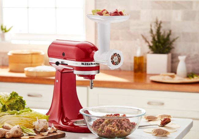 Close-up of KitchenAid meat grinder attachment connected to a stand mixer.