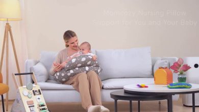 Mom smiling while breastfeeding newborn on Momcozy nursing pillow in cozy nursery