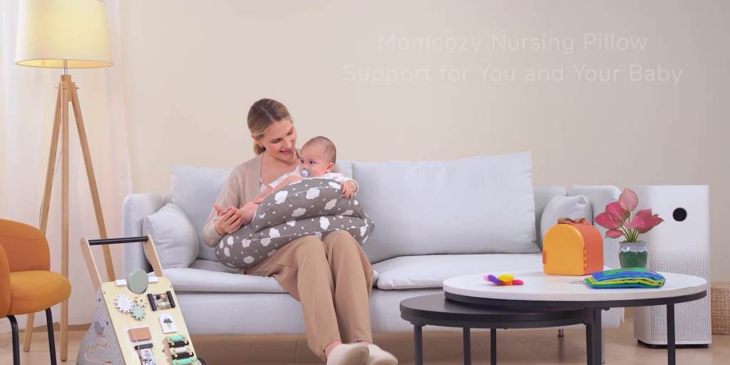 Mom smiling while breastfeeding newborn on Momcozy nursing pillow in cozy nursery