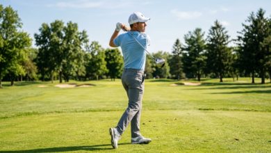A golfer wearing a white breathable mesh-back golf cap while standing on a sunny fairway mid-swing