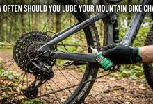 Applying liquid lubricant to a clean mountain bike chain on a trail.