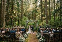 A rustic floral arch stands ready for a wedding ceremony in a Washington pine forest.