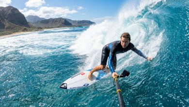 Surfer holding a waterproof camera while riding an ocean wave.