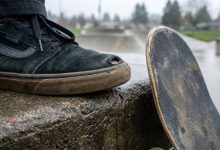 Skateboarder inspecting a worn toe on a skate shoe