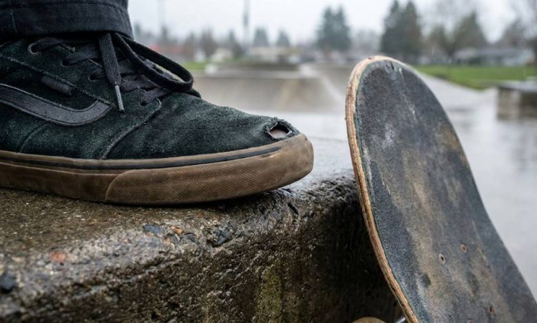 Skateboarder inspecting a worn toe on a skate shoe