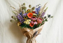 Colorful wildflower bouquet wrapped in rustic brown paper on a table.