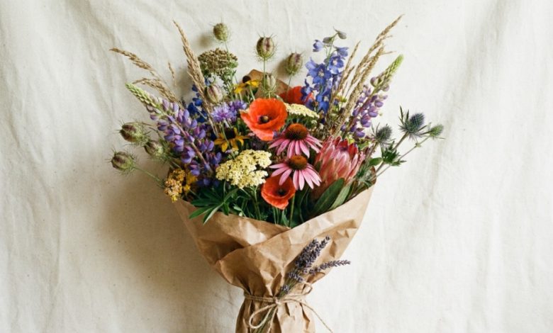 Colorful wildflower bouquet wrapped in rustic brown paper on a table.
