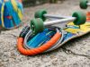 A skateboard secured to a metal bike rack using a heavy-duty U-lock.